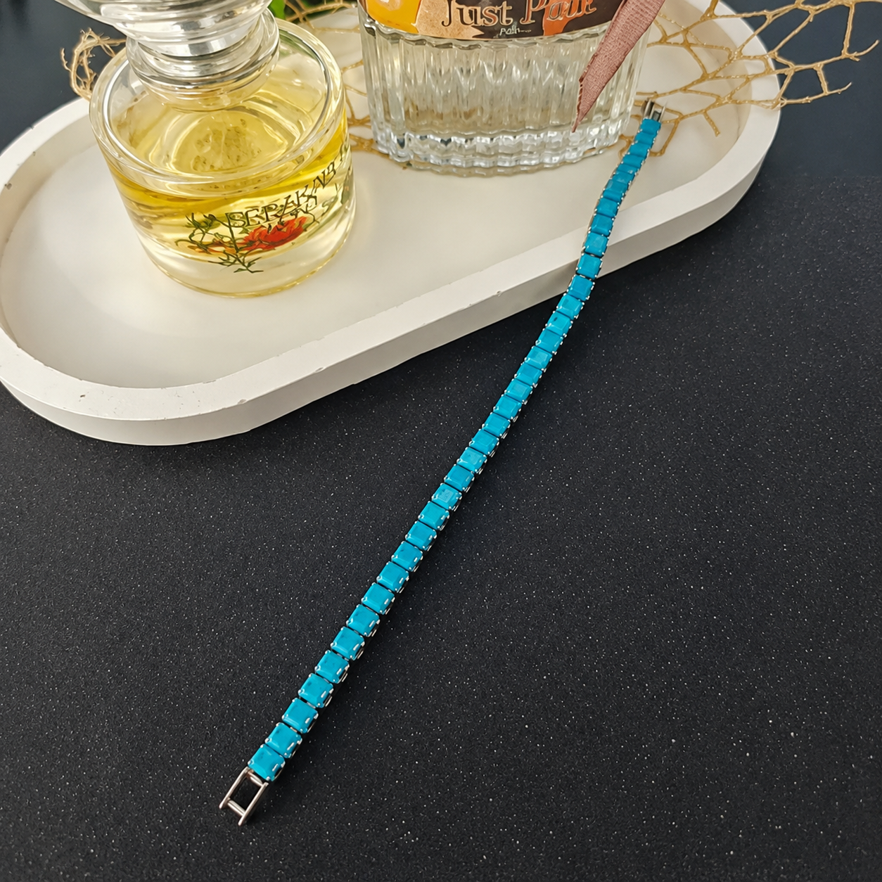 Light blue square bead bracelet with metallic clasp displayed beside a decorative white tray