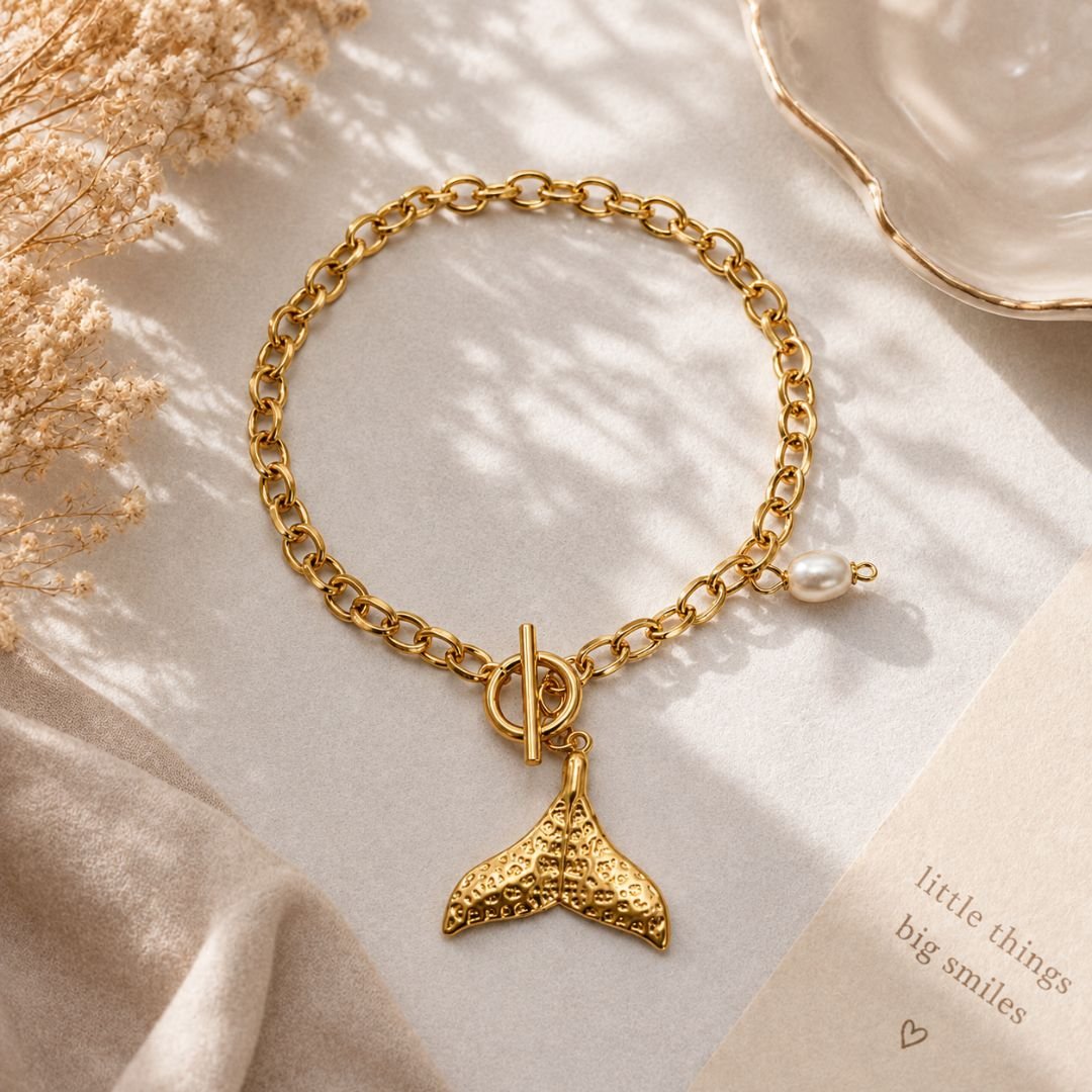 Premium golden whale tail bracelet with gold-tone chain, whale tail charm and faux pearl accent.