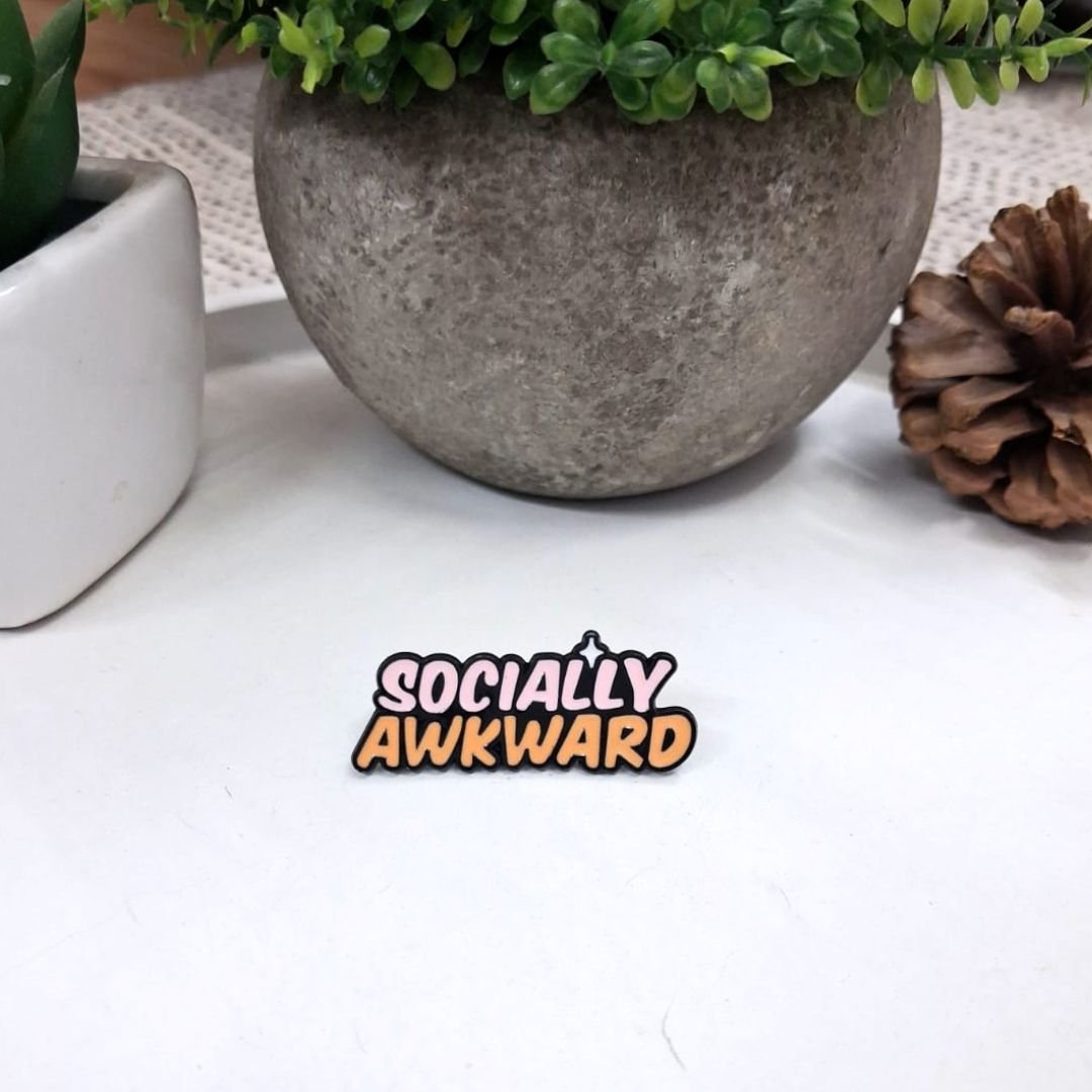 socially awkward lapel pin placed on a table with plant decor