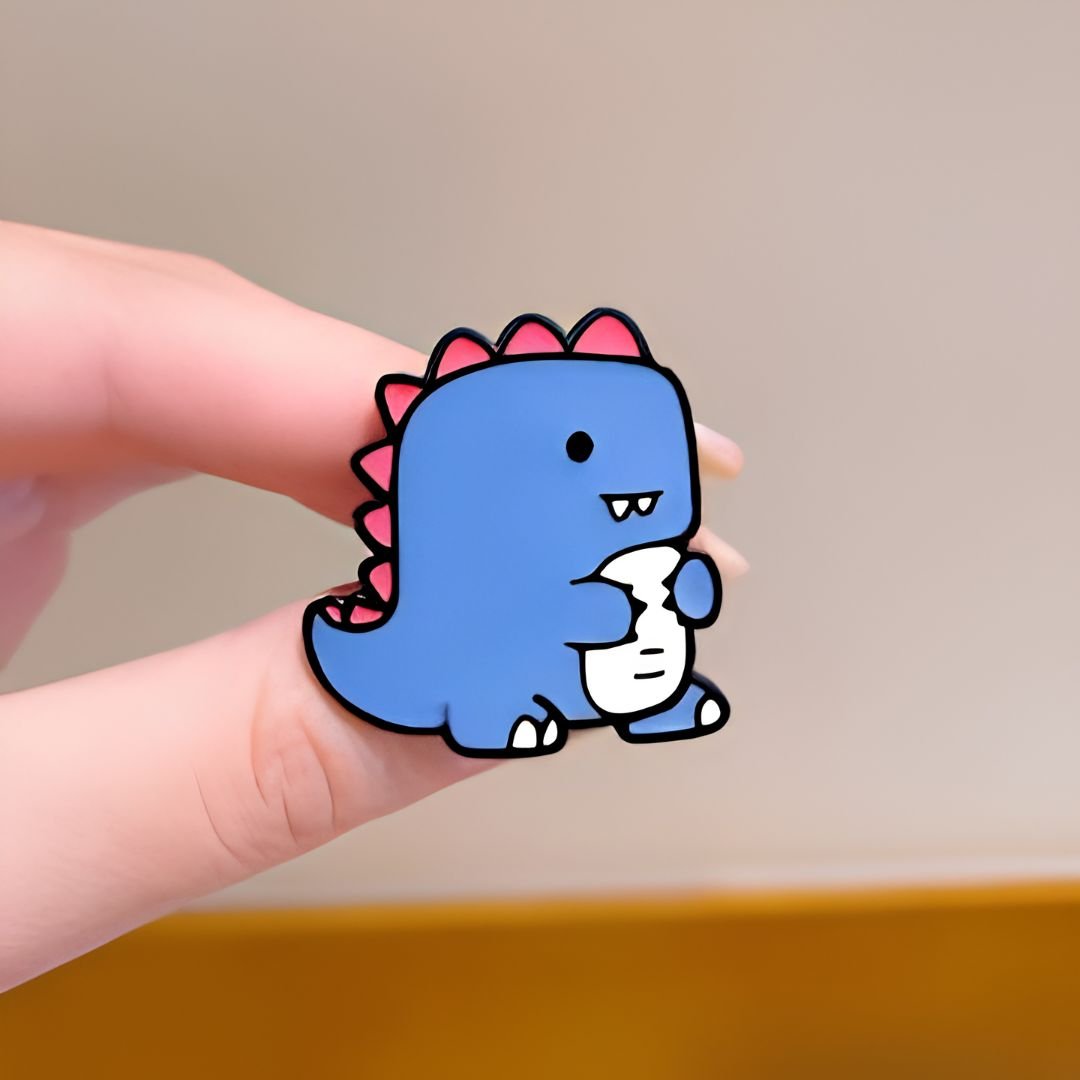 Baby dinosaur enamel pin blue dino with pink spines hugging egg cute kawaii lapel pin held in hand