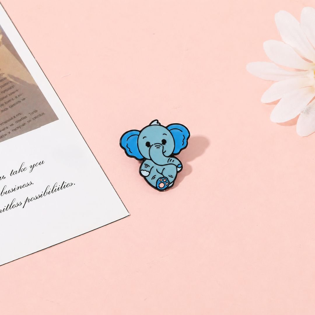 Baby elephant enamel pin cute blue kawaii lapel pin flat lay on pink background with flowers