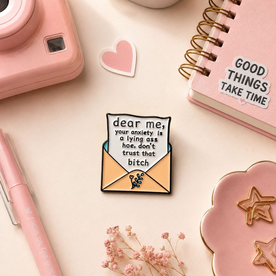 Premium Dear Me anxiety reminder enamel pin featuring a motivational envelope design with polished black metal detailing.